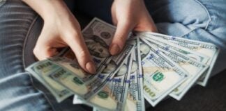 Woman fanning a pile of U.S. 100 dollar bills.