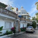 A car parked in front of a white, Moorish building in Puerto Vallarta.