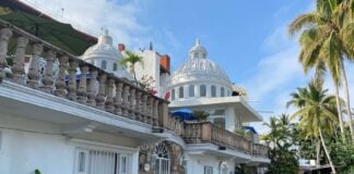 A car parked in front of a white, Moorish building in Puerto Vallarta.