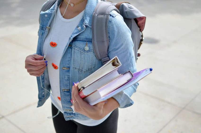 Female college student carrying books and a backback
