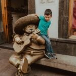 Boy playing by a statue of a mariachi playing a guitar in Guadalajara