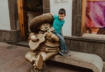 Boy playing by a statue of a mariachi playing a guitar in Guadalajara