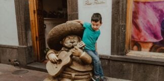 Boy playing by a statue of a mariachi playing a guitar in Guadalajara