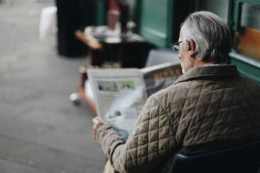 Man reading a newspaper at a cafe