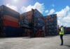 A shipyard worker surveys piles of export shipping containers