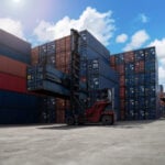 A shipyard worker surveys piles of export shipping containers