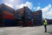 A shipyard worker surveys piles of export shipping containers