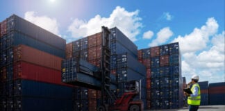 A shipyard worker surveys piles of export shipping containers