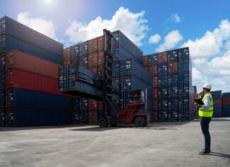 A shipyard worker surveys piles of export shipping containers