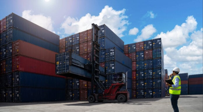 A shipyard worker surveys piles of export shipping containers