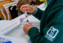 A nurse wearing an IMSS uniform draws a vaccine