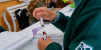 A nurse wearing an IMSS uniform draws a vaccine