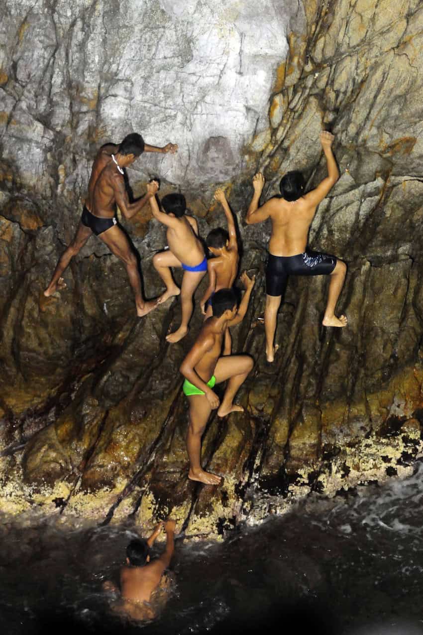 5 boys and 1 man climb a cliff in Acapulco, as if rockclimbing