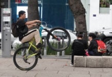 A young man on a bicycle pops a wheelie as he rides down Paseo de La Reforma in Mexico City.
