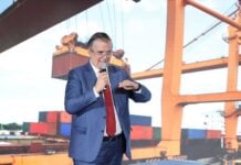 Ebrard standing in front of a presentation featuring an image of shipping containers