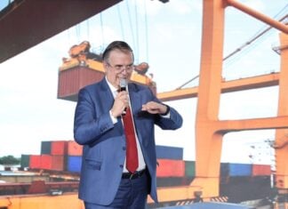 Ebrard standing in front of a presentation featuring an image of shipping containers