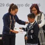 President Sheinbaum presents a scholarship card to a young boy