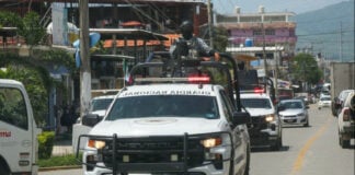 National Guard vehicles drive in a line through and urban area during a September operation in Coyuca de Benítez, Guerrero.