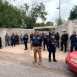 Police, emergency services and Civil Protection outside the cinder block fence and entrance of a school