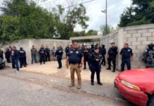 Police, emergency services and Civil Protection outside the cinder block fence and entrance of a school