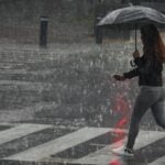 woman walking with an umbrella through heavy rain