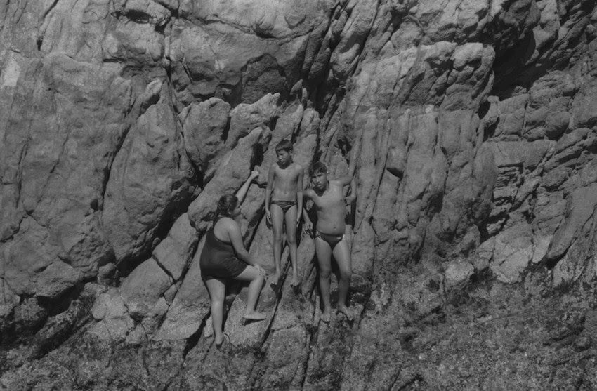 Black and white shot of young boys and a girl waiting on a cliff, photo taken from the film