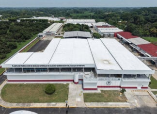 An industrial facility in a lush Chiapas forest with a sign reading "Planta de Producción de Moscas Estériles del Gusano Barrenador del ganado en Metapa"