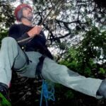 Arborist Juan Carlos Velázques Hueso climbing to saw off branches affected by el muérdago