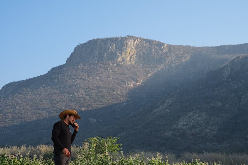 A man talking on the phone withn a mountain in the background