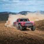 Kicking up desert dust as a car goes off-road during the 2025 Baja 1000 race.