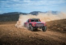 Kicking up desert dust as a car goes off-road during the 2025 Baja 1000 race.