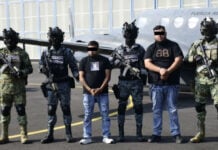Mexican security forces stand with two men in handcuffs