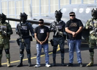Mexican security forces stand with two men in handcuffs
