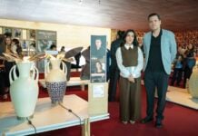 Two designers stand next to their artworks in a gallery.