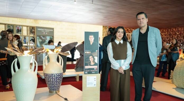 Two designers stand next to their artworks in a gallery.