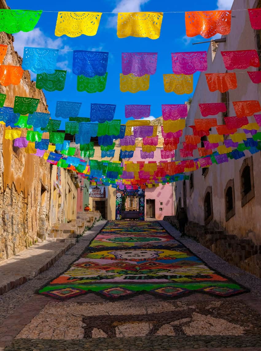 Día de Muertos street mural below papel picado