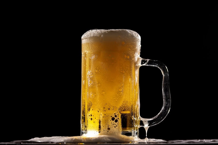 Mug of sudsy draft beer against a black background