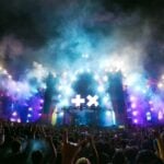 Live music concert experience in Zapopan, with fans holding up rock on signs as they mass in front of the smoky stage