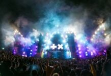 Live music concert experience in Zapopan, with fans holding up rock on signs as they mass in front of the smoky stage