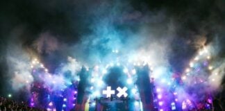 Live music concert experience in Zapopan, with fans holding up rock on signs as they mass in front of the smoky stage