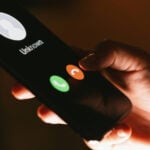 A closeup shows a hand pushing the decline button on an unknown call, on a smartphone