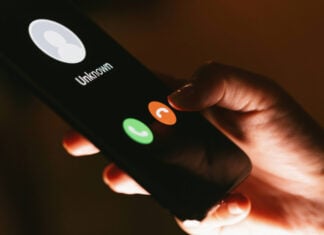 A closeup shows a hand pushing the decline button on an unknown call, on a smartphone