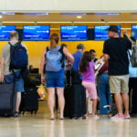 Airline passengers wait in line with baggage at a United kiosk at Cancún International Airport