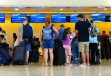 Airline passengers wait in line with baggage at a United kiosk at Cancún International Airport