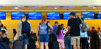 Airline passengers wait in line with baggage at a United kiosk at Cancún International Airport