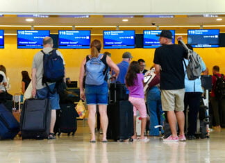 Airline passengers wait in line with baggage at a United kiosk at Cancún International Airport