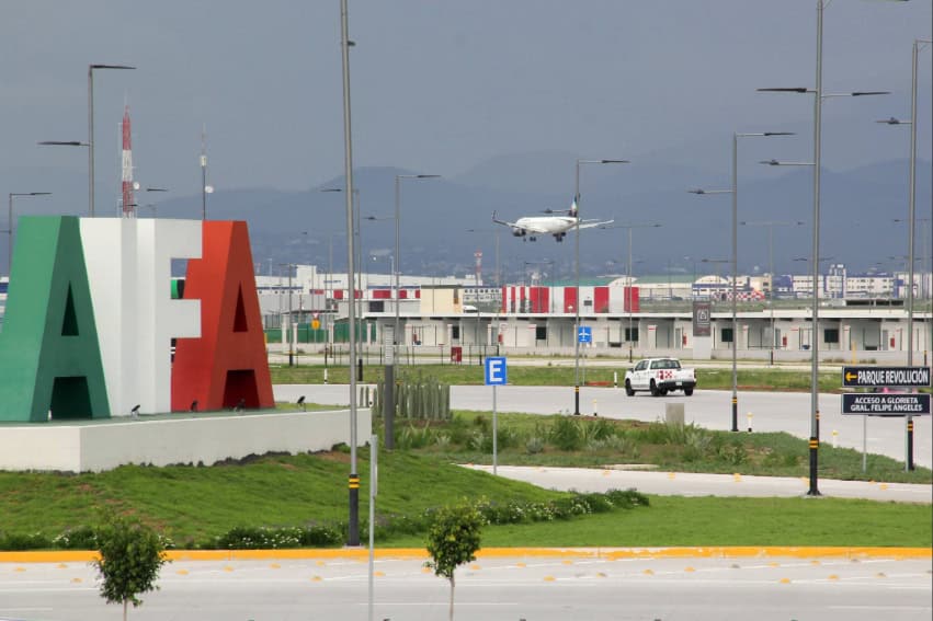 AIFA airport entrance sign with an airplane in the background taking off