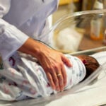 A doctor checks on a newborn in the NICU