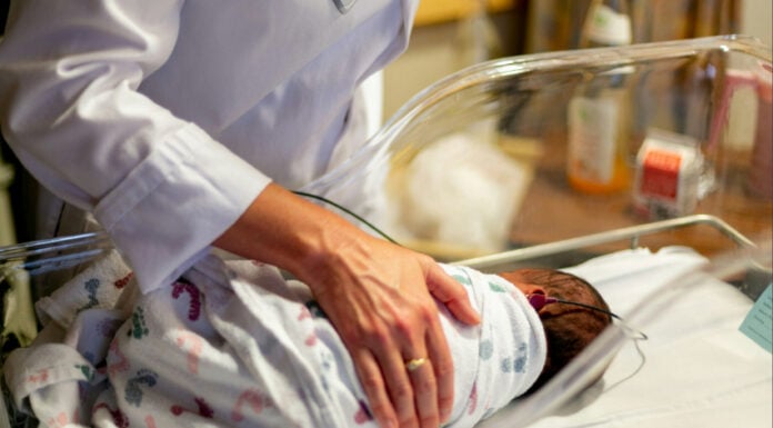 A doctor checks on a newborn in the NICU